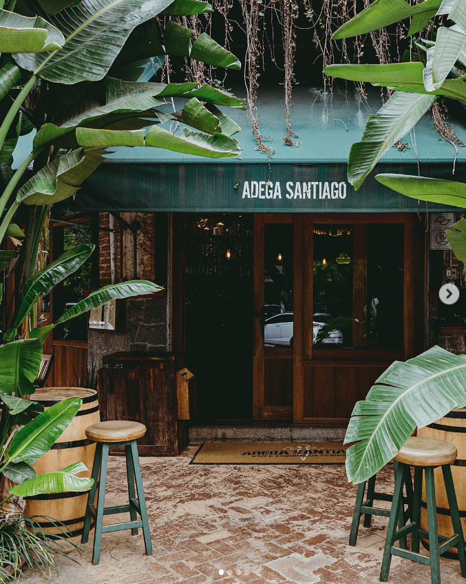 Fachada da Adega Santiago com bananeiras e toldo verde